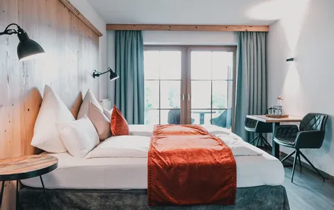 Spielberg Modernes Hotelzimmer mit Doppelbett, roter Tagesdecke, Schreibtisch und Balkonzugang